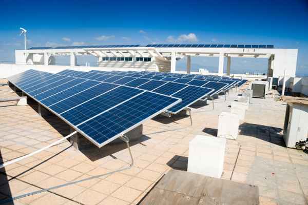Quale tipo di pannello solare è il migliore per uso commercialeun complesso industriale in background Large ground-mounted solar farm powering an industrial complex in the background