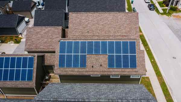 يمكن تخزين البطاريات مكدسة�لواح الشمسية An image of a roof with 7 solar panels, with an arrow pointing to a 10kWh wall-mounted battery being charged.