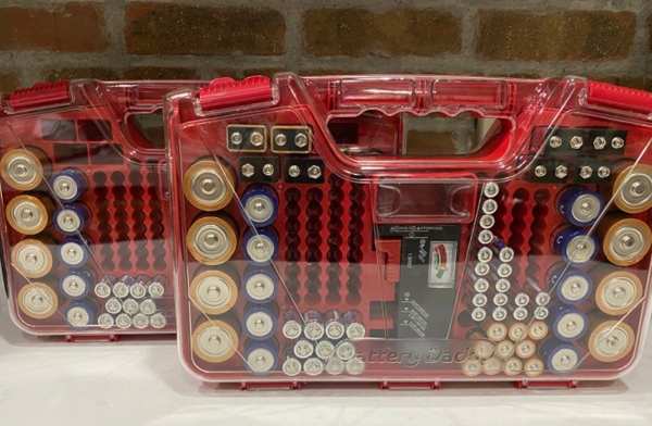 A storage box shown two ways. One side has loose batteries jumbled together with a red 